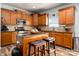 Kitchen featuring wood cabinets, stainless steel appliances, an island with stools, and tile backsplash at 8909 Savannah Rd, Harrisburg, NC 28075