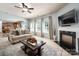 Open living room with a fireplace, large windows, and a clear view of the adjacent kitchen at 8909 Savannah Rd, Harrisburg, NC 28075