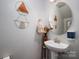 Cozy powder room featuring a pedestal sink, decorative mirror, and modern decor at 8909 Savannah Rd, Harrisburg, NC 28075
