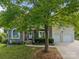Charming stone and stucco home with a manicured lawn, mature tree, and a welcoming front porch at 9038 Sandpiper Dr, Charlotte, NC 28277
