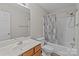 Well-lit bathroom features a shower-tub combo, wooden vanity, neutral walls, and updated fixtures at 12516 Hennigan Place Ln, Charlotte, NC 28214