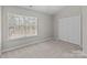 This is a bedroom with a large window providing natural light and a closet for storage at 12516 Hennigan Place Ln, Charlotte, NC 28214