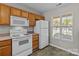 Kitchen features wood cabinets, white appliances, and a window for natural light at 12516 Hennigan Place Ln, Charlotte, NC 28214
