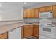Functional kitchen featuring wood cabinets, white appliances, and an open layout to the living area at 12516 Hennigan Place Ln, Charlotte, NC 28214