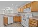 Functional kitchen featuring wood cabinets, white appliances, and an open layout to the living area at 12516 Hennigan Place Ln, Charlotte, NC 28214