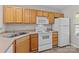 Functional kitchen featuring wood cabinets, white appliances, and an open layout to the living area at 12516 Hennigan Place Ln, Charlotte, NC 28214