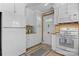 Well-lit kitchen featuring white cabinets, appliances, neutral countertops, and tiled floor, creating a cozy cooking space at 135 Burton Hills Cir, Gastonia, NC 28054