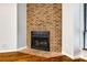 Close-up of a brick fireplace with a black grate and wood flooring at 1606 Sharon W Rd # 40, Charlotte, NC 28210