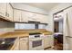 A kitchen area featuring white appliances and cabinets, tiled floors, and a view of the living room at 1606 Sharon W Rd # 40, Charlotte, NC 28210