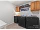 Well-organized laundry room features modern washer and dryer, ample cabinet space, and decorative wallpaper at 17231 Rider Wood Ln, Charlotte, NC 28278
