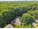 Aerial view of homes surrounded by a dense forest, with a glimpse of rooftops amidst the green canopy at 212 Foxfield Ln, Matthews, NC 28105
