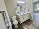 Bright bathroom with a toilet, a double vanity, a framed mirror, modern fixtures, gray walls, and wood look floors at 325 Jordan Ave, Salisbury, NC 28159