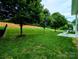 Spacious backyard with lush green grass, a charming fence, and mature trees at 408 Presidio Dr, Rock Hill, SC 29732