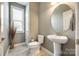 Half bath with pedestal sink, round mirror, and neutral color palette at 4220 Thames Cir, Fort Mill, SC 29715
