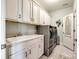 Bright laundry room with stainless steel washer and dryer, ample cabinet space, and a utility sink at 4220 Thames Cir, Fort Mill, SC 29715