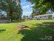 View of the expansive backyard featuring a brick fire pit, grassy lawn, and shade trees at 427 E 12Th Ave, Gastonia, NC 28054