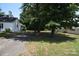 View of the side of a one-story home surrounded by mature shade trees at 506 Linwood Rd, Gastonia, NC 28052