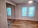 Bedroom with mirrored closet doors, neutral walls, two windows and wood-look flooring at 616 Laurel St, Albemarle, NC 28001