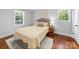 Bright bedroom with a yellow floral bedspread, wooden floors, and natural light from two large windows at 6733 Candlewood Dr, Charlotte, NC 28210