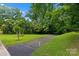 Lush green front lawn featuring a paved driveway leading to a home surrounded by mature trees and landscaping at 6733 Candlewood Dr, Charlotte, NC 28210