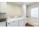 Bright laundry room with white cabinets and countertops, stainless steel sink, and access to the outside at 7627 Sarah Dr, Denver, NC 28037