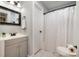 This bathroom features a shower with a white curtain, and a grey vanity with a black faucet at 8135 Cedar Glen Dr, Charlotte, NC 28212