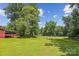 Picture of a large backyard surrounded by mature trees, a wooden fence and an outbuilding at 8706 Richardson King Rd, Waxhaw, NC 28173