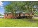 Charming red brick home featuring a well-manicured lawn, mature trees, and inviting curb appeal at 8706 Richardson King Rd, Waxhaw, NC 28173