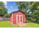 Exterior view of a red shed with double doors and an adjacent covered shelter in the backyard at 8706 Richardson King Rd, Waxhaw, NC 28173