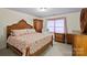Cozy bedroom with a patterned bedspread, wood furniture, and a bright window with covering at 8918 Beach Bluff Ct, Sherrills Ford, NC 28673