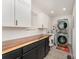 Well-lit laundry room featuring stacked washer/dryer, wood countertop, and white cabinetry at 157 Downey Lake Rd, Dallas, NC 28034