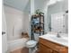 Bathroom with wood cabinet sink, shower/tub combo, and storage shelves at 163 Sassafras Rd, Mooresville, NC 28115