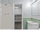 This bathroom features white tile walls and a vanity with green wood paneling and an open doorway to the laundry room at 2000 Townsend Ave, Charlotte, NC 28205