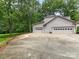 Spacious three car garage with white doors and concrete driveway surrounded by lush green trees at 2141 Halford Pl, Charlotte, NC 28211