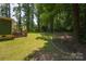 Large, level backyard features mature trees, a brick patio, and a green home exterior at 215 W Eastway Drive Dr, Charlotte, NC 28213