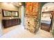 The bright bathroom boasts a double vanity and a brick facade next to the arched doorway to the bedroom at 215 W Eastway Drive Dr, Charlotte, NC 28213