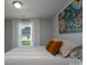 Cozy bedroom featuring a comfortable bed with decorative pillows, a colorful floral painting, and a window with sheer curtains at 360 Sexton St, Kannapolis, NC 28081