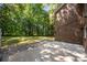Brick house backyard with a concrete patio and lush green lawn surrounded by tall trees at 4444 Steepleton Way, Charlotte, NC 28215