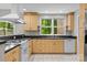 Well-lit kitchen featuring light wooden cabinetry, black countertops, and a window overlooking a lush green yard at 4444 Steepleton Way, Charlotte, NC 28215