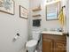 Cozy powder room featuring floral wall art, floating shelves, and a wood vanity with sink at 5701 Silver Eagle Dr, Charlotte, NC 28214