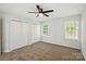 A bedroom with ceiling fan, neutral carpet, closet and two windows offers a serene space at 5717 Fairchase Ave, Charlotte, NC 28269