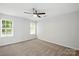 An empty bedroom with a ceiling fan and neutral carpet showcases bright, natural light at 5717 Fairchase Ave, Charlotte, NC 28269