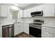 Bright kitchen featuring white cabinets, stainless steel appliances, tile backsplash, and modern countertops at 5717 Fairchase Ave, Charlotte, NC 28269