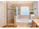 This bathroom offers a shower with glass doors, a soaking tub with a glass block window at 7521 Plumcrest Ln, Harrisburg, NC 28075