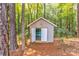 Storage shed in wooded backyard with open doors, showing the interior at 7521 Plumcrest Ln, Harrisburg, NC 28075