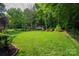 Expansive backyard featuring lush greenery and a storage shed, ideal for outdoor activities and storage at 7988 Golf Course N Dr, Denver, NC 28037