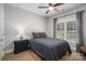 A comfy bedroom with a ceiling fan, a window with curtains, and a dark-stained nightstand at 7988 Golf Course N Dr, Denver, NC 28037