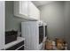 Well-equipped laundry room with white cabinets and modern washer and dryer units for efficient chores at 7988 Golf Course N Dr, Denver, NC 28037