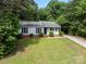 Inviting one-story house with lush front lawn, black shutters, and complemented by surrounding trees at 10016 Heathergate Ln, Mint Hill, NC 28227