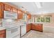 Kitchen featuring white appliances, wood cabinets, double sink and adjacent eat-in area with big window at 103 Prestwick Ct, Salisbury, NC 28146